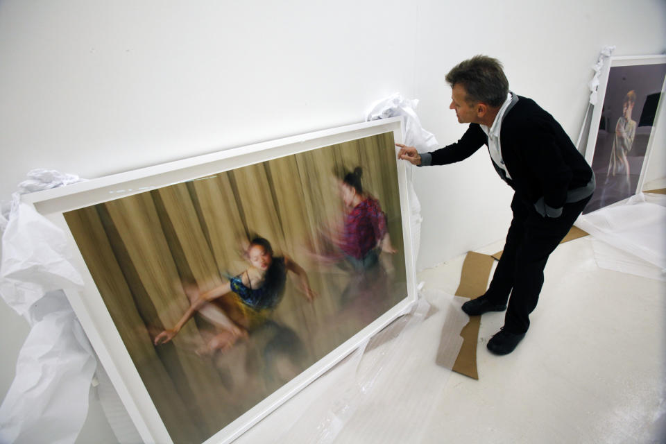 In this Tuesday, Feb. 21, 2012 photo, dancer Mikhail Baryshnikov, talks about one of his photographs during an interview with The Associated Press, before the photos are hung at the Gary Nader Art Centre in Miami. The show, which opens Friday, Feb. 24, is titled “Dance This Way” and features large-scale photographs of ethnic, hip-hop, ballet, modern and popular dances performed on stage by professionals and in nightclubs by amateurs. (AP Photo/Wilfredo Lee)