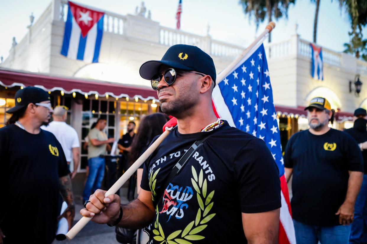 Henry “Enrique” Tarrio carries an American flag at a protest.