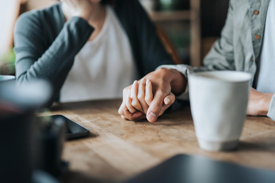 A couple holds hands at a cafe