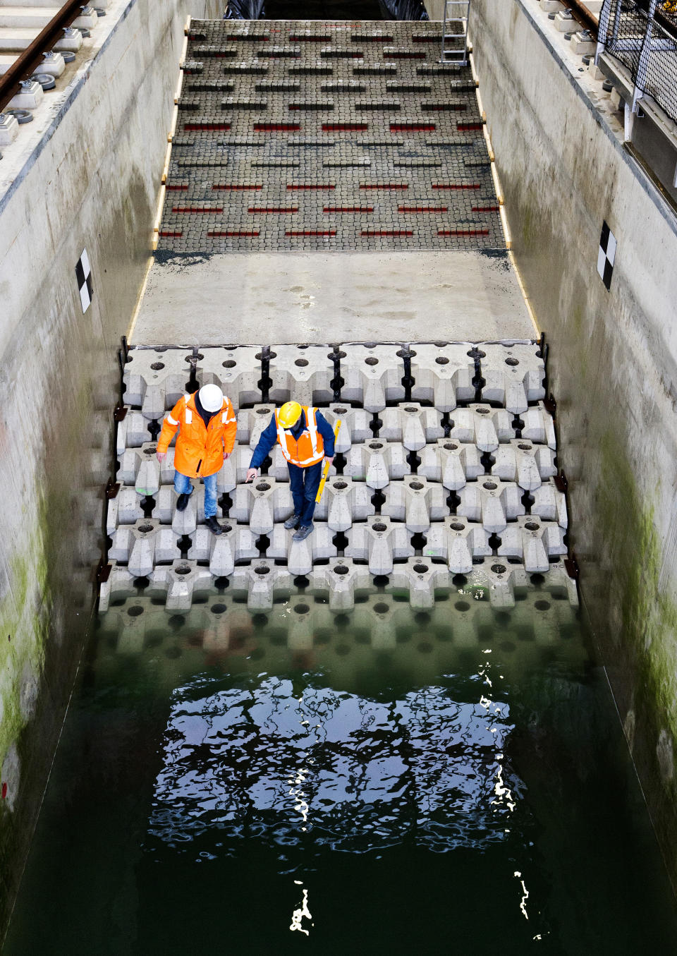 This photo taken in Jan. 2019 and made available by Deltares shows the flume wave tank in Delft, Netherlands, that is used to test structure designs for the strengthening work for the Afsluitdijk. With climate change bringing bigger storms and rising sea levels, one of the low-lying Netherlands’ key defenses against the sea is getting a major makeover. The 5-year project will see workers lay thousands of concrete blocks and raise parts of the 87-year-old Afsluititdijk dike. (Guus Schoonewille/Deltares via AP)