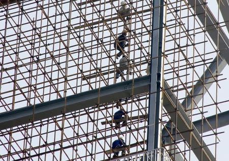 Labourers work on scaffolding of a construction site of a residential and commercial complex in Beijing, China, September 18, 2015. REUTERS/Kim Kyung-Hoon