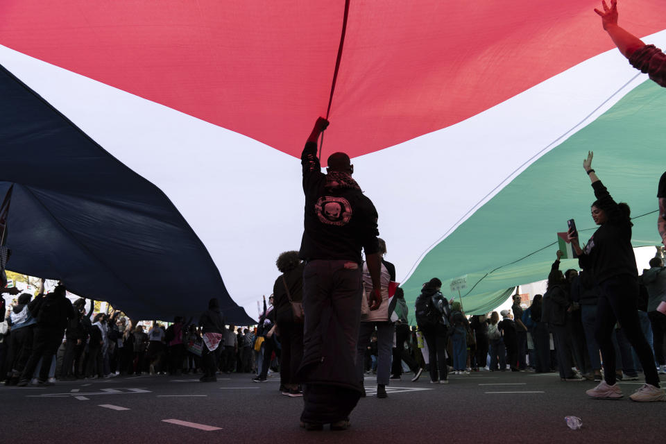 Anti-war activists rise a Palestinian flag during a pro-Palestinian demonstration asking to cease fire in Gaza, at Freedom Plaza in Washington, Saturday, Nov. 4, 2023. (AP Photo/Jose Luis Magana)