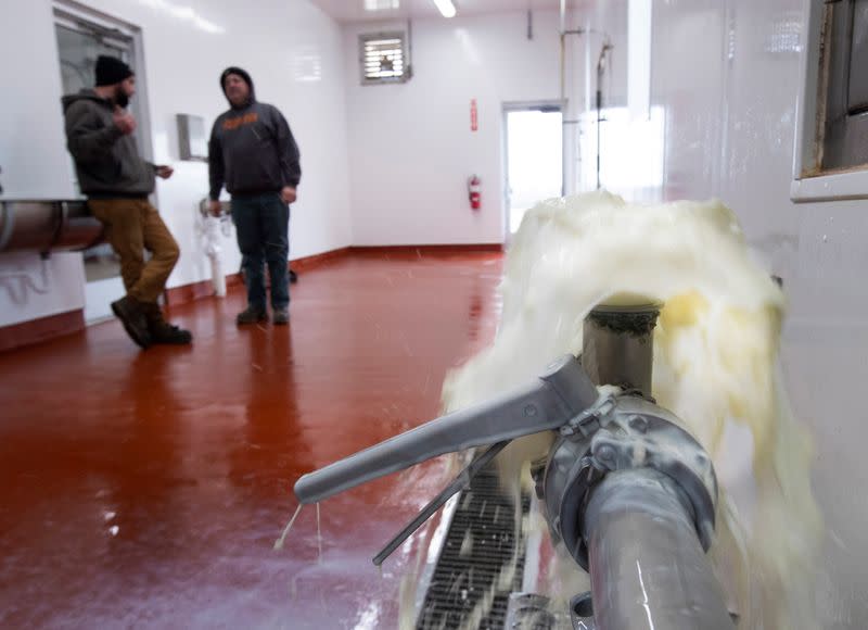 Ryan Eble and his father Chris talk in their milk house at the Eble family's Golden E Dairy farm near West Bend, Wisconsin