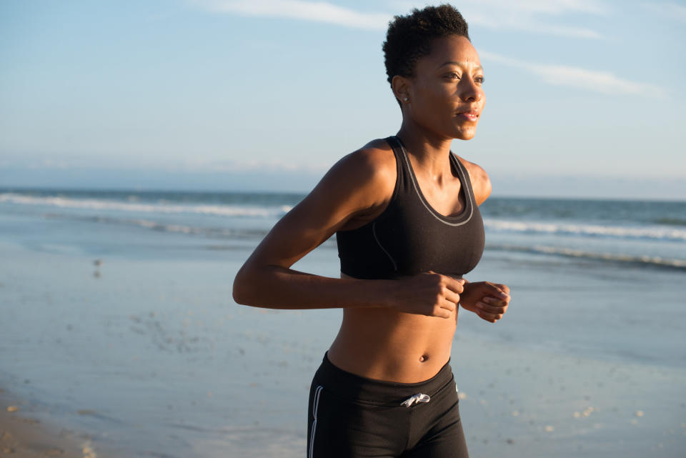 A woman jogs on the beach without headphones