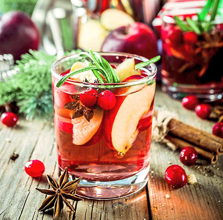 Wreaths decorating party: Holiday winter sangria with fruit and spices served in glass on a wooden tabletop