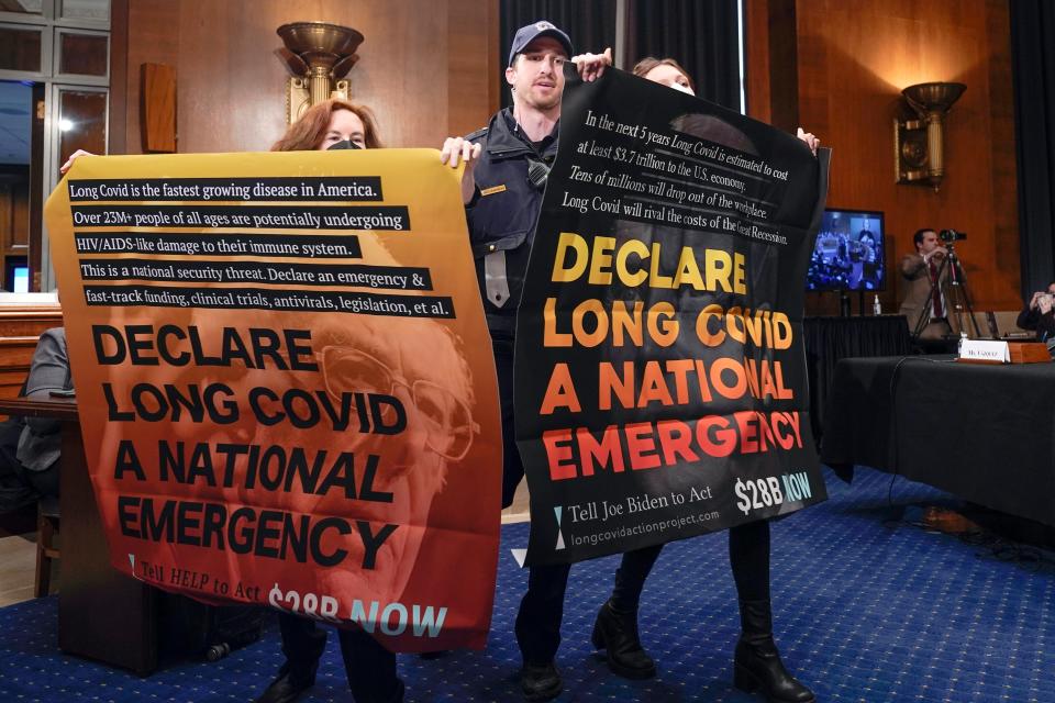 People protest during a Senate hearing on long COVID-19 on Jan. 18.