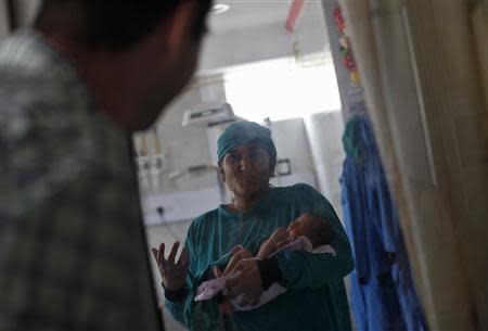 Rekha Patel, 42, holds her week-old-baby girl Gabriella, while speaking to her husband Daniele Fabbricatore, 39, at the Akanksha IVF centre in Anand town, about 70 km (44 miles) south of the western Indian city of Ahmedabad August 25, 2013. REUTERS/Mansi Thapliyal