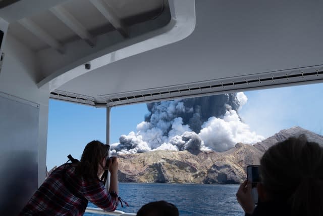 Tourists on a boat look at the eruption of the volcano on White Island, New Zealand