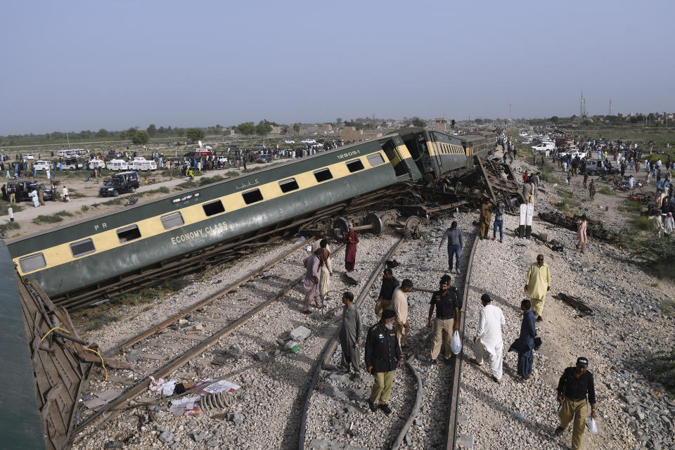 Police officers and local residents gather at the site of a passenger train derailed near Nawabshah, Pakistan, Sunday, Aug. 6, 2023. Railway officials say some passengers were killed and dozens more injured when a train derailed near the town of Nawabshah in southern Sindh province. (AP Photo/Umair Ali)