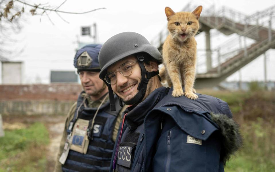 AFP journalist Arman Soldin smiles to photographer as a cat stands on his shoulders during an assignment for AFP in Ukraine on November 11, 2022 - BULENT KILIC/AFP