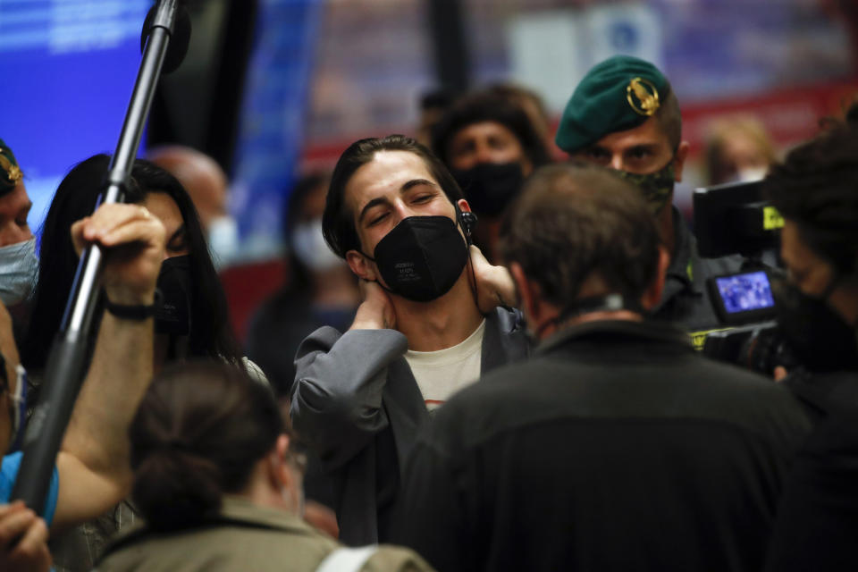 Damiano David of Italian band Maneskin, center, listens to reporters' questions upon their arrival at Rome's Fiumicino airport, Sunday, May 23, 2021. The glam rock band who got their start busking on Rome's main shopping drag won the Eurovision Song Contest Saturday and brought next year's competition back to the place where Europe's song contests began. (AP Photo/Alessandra Tarantino)