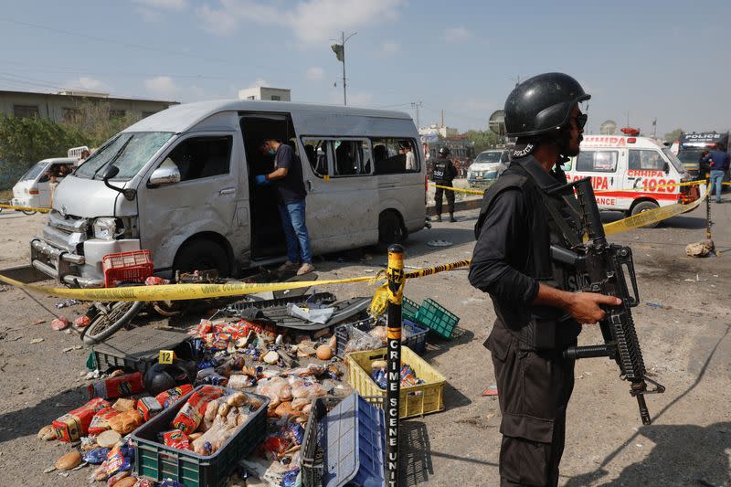 Police officer stands guard near a cordoned damaged vehicle after a suicide blast in Karachi