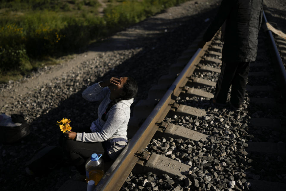 A Venezuelan migrant laughs as she jokes with her husband, who gave her a few flowers he picked in the grass, as they wait along the rail lines in hopes of boarding a freight train heading north in Huehuetoca, Mexico, Wednesday, Sept. 20, 2023. The image was part of a series by Associated Press photographers Ivan Valencia, Eduardo Verdugo, Felix Marquez, Marco Ugarte Fernando Llano, Eric Gay, Gregory Bull and Christian Chavez that won the 2024 Pulitzer Prize for feature photography. (AP Photo/Eduardo Verdugo)