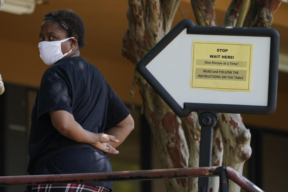 A client stands outside this Mississippi Department of Employment Security WIN Job Center in Pearl, Miss., and waits for assistance from a staffer, Monday, Aug. 31, 2020. Because the Job Center lobbies are currently closed to prevent the spread of COVID-19, some locations are providing outdoor walkup assistance while maintaining social distancing and face masking to protect both parties. (AP Photo/Rogelio V. Solis)