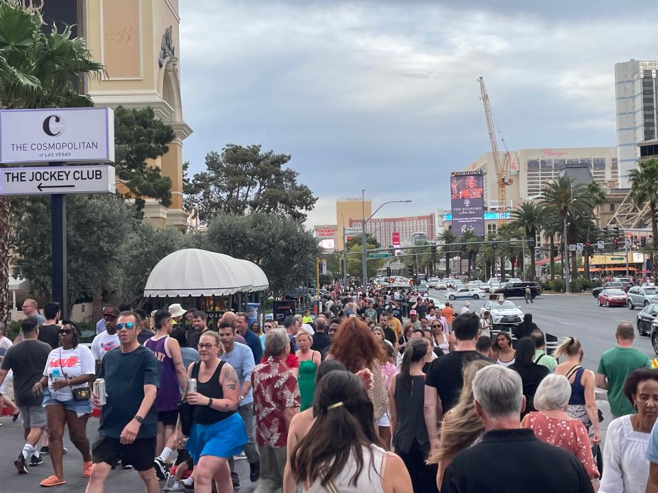 A large crowd of people walking on the Las Vegas Strip on a cloudy day.