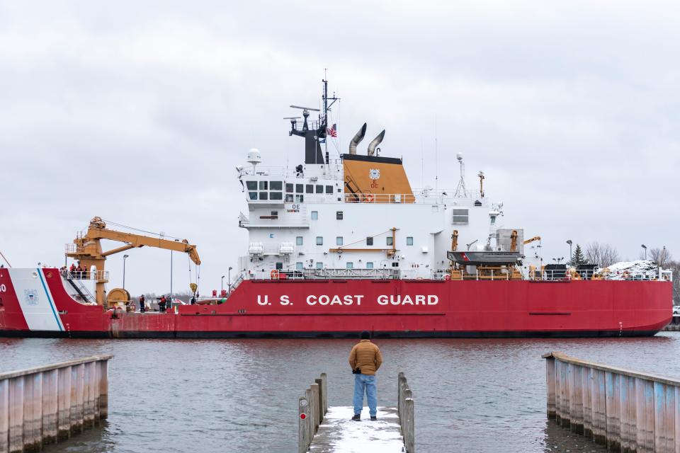 A spectator views the U.S. Coast Guard Cutter Mackinaw from a dock at the Cheboygan County Marina on Sunday, Nov. 26, 2023.