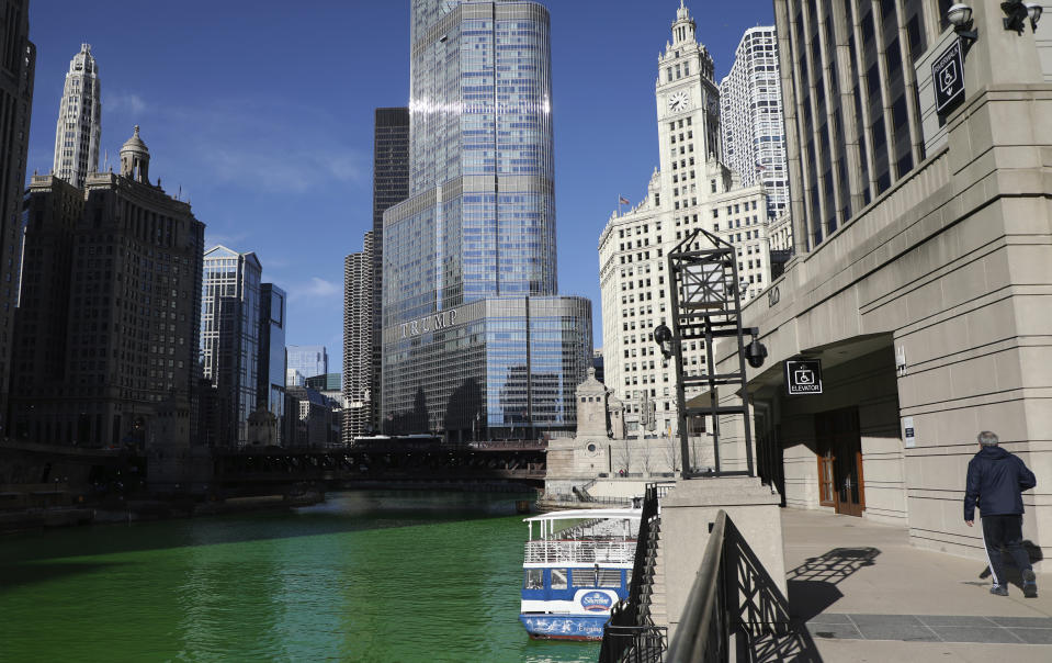 People catch glimpses of the Chicago River dyed green in celebration of St. Patrick's Day on Saturday, March 13, 2021 in Chicago. Mayor Lightfoot sanctioned the famous river dyeing to proceed Saturday, but the Riverwalk was closed to minimize the number of people gathering due to COVID-19. (Abel Uribe /Chicago Tribune via AP)