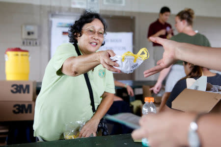 A volunteer distributes free dust masks in Keaau to protect against volcanic ash during ongoing eruptions of the Kilauea Volcano in Hawaii, U.S., May 17, 2018. REUTERS/Terray Sylvester