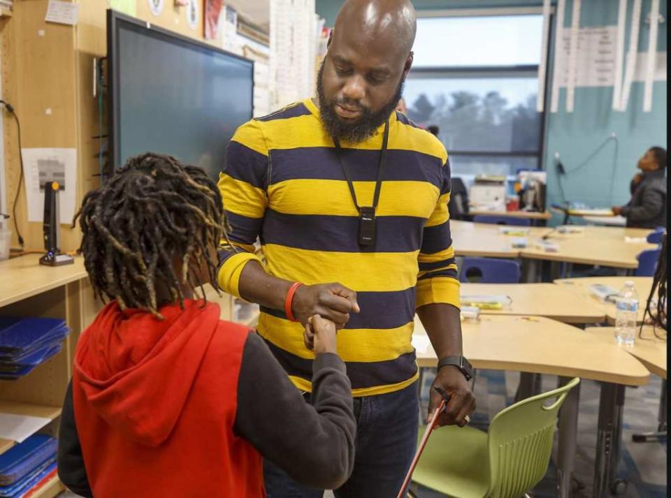 Tyler Wright (right) congratulates one of his fourth-grade students with a fist bump at Stono Park Elementary School in Charleston, South Carolina, in November 2022. There’s a new generation of Black men choosing teaching. (Photo by Grace Beahm Alford/The Post And Courier via AP)