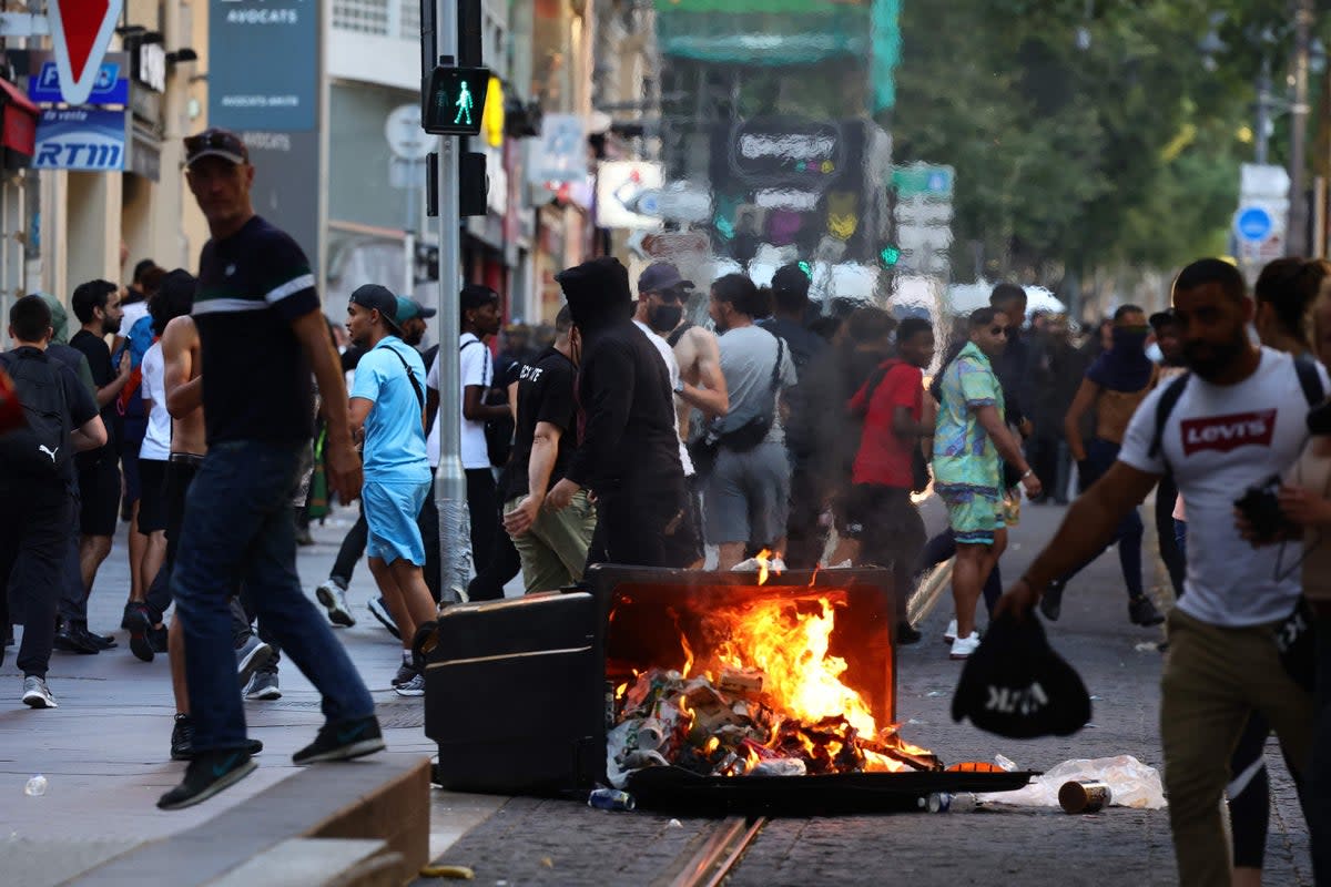 Protesters walk past a burnt out trash bin during clashes with police in Marseille (AFP via Getty Images)
