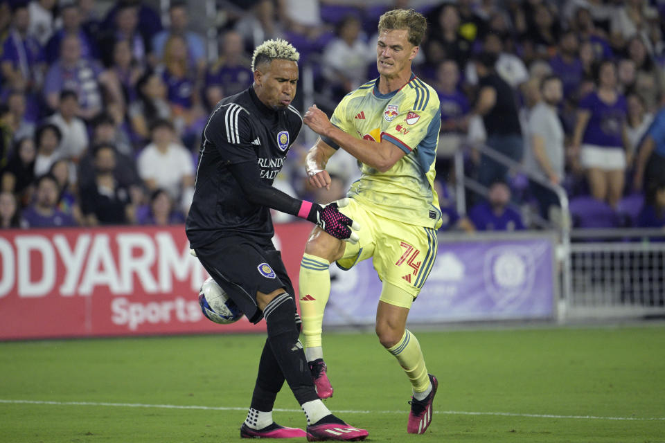 Orlando City goalkeeper Pedro Gallese, left, and New York Red Bulls forward Tom Barlow (74) collide while going for the ball during the first half of an MLS soccer matc Saturday, Feb. 25, 2023, in Orlando, Fla. (AP Photo/Phelan M. Ebenhack)