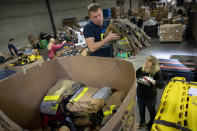 Dmytro Malymonenko loads used jackets into a bin with help from Valeriya Roshkovan, right, as they volunteer with Razom for Ukraine, a New York-based nonprofit, to help package donated firefighting equipment to ship to her country, Wednesday, Feb. 8, 2023, in Woodbridge Township, N.J. (AP Photo/John Minchillo)