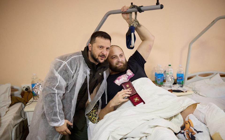 Ukraine's President Volodymyr Zelenskiy poses for a picture with an injured Ukrainian serviceman in a hospital after his visit a frontline