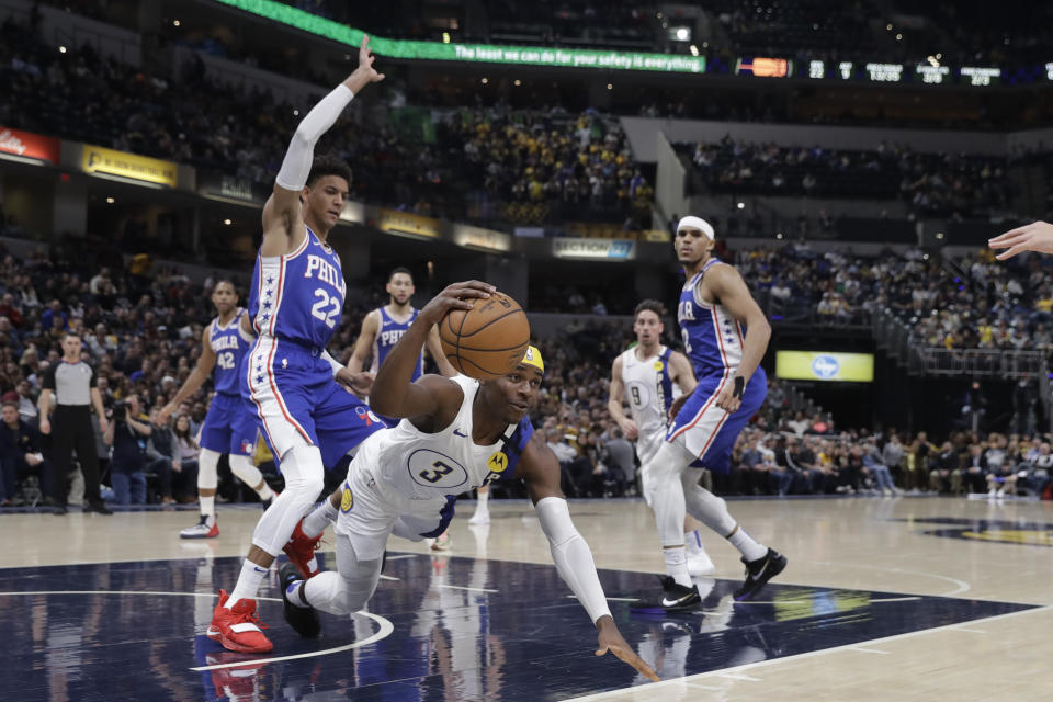 Indiana Pacers' Aaron Holiday (3) falls to the court as he is defended by Philadelphia 76ers' Matisse Thybulle (22) during the first half of an NBA basketball game, Monday, Jan. 13, 2020, in Indianapolis. (AP Photo/Darron Cummings)