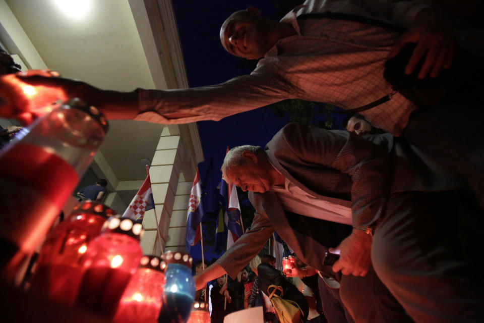 People place candles by posters reading "not my president" during protest in Mostar, Bosnia, Thursday, Oct. 11, 2018. Several thousand Bosnian Croat nationalists have protested the election victory of a moderate politician last weekend in the race for the Croat seat in Bosnia's three-person presidency. The crowd Thursday marched through the ethnically divided southern town of Mostar holding banners reading "Not my president" and "RIP democracy" in protest at the election of Zeljko Komsic." (AP Photo/Amel Emric)