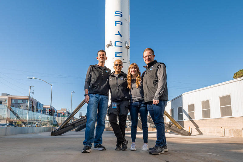 The crew poses in front of a SpaceX Falcon 9 first stage booster on display at company headquarters in Hawthorne, California. / Credit: Inspiration4