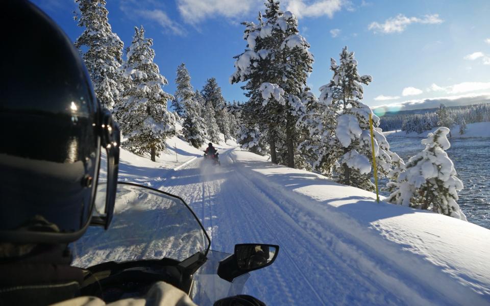 Rider snowmobiling in Yellowstone National Park, Wyoming holidays, winter - Getty