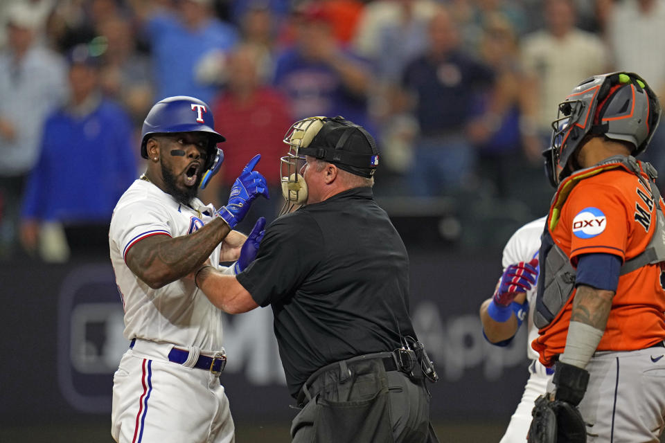 Home Plate umpire Marvin Hudson, center, restrains Texas Rangers' Adolis Garcia, left, as he yells at Houston Astros catcher Martin Maldonado after being hit by a pitch during the eighth inning in Game 5 of the baseball American League Championship Series Friday, Oct. 20, 2023, in Arlington, Texas. (AP Photo/Julio Cortez)