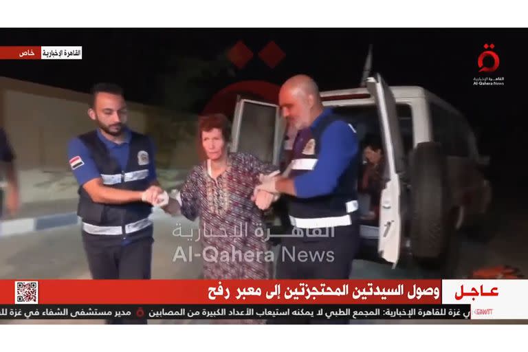 En esta imagen tomada de un video publicado por al-Qahera News, Yocheved Lifshitz, de 85 años, es asistida por la Cruz Roja hasta las ambulancias que esperan en el cruce de Rafah. 