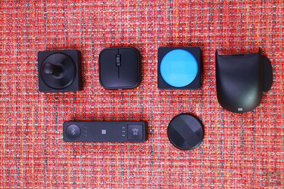 <p>The Microsoft Adaptive Mouse, Hub, Tail and two Buttons with different toppers, laid out on an ottoman.</p> 