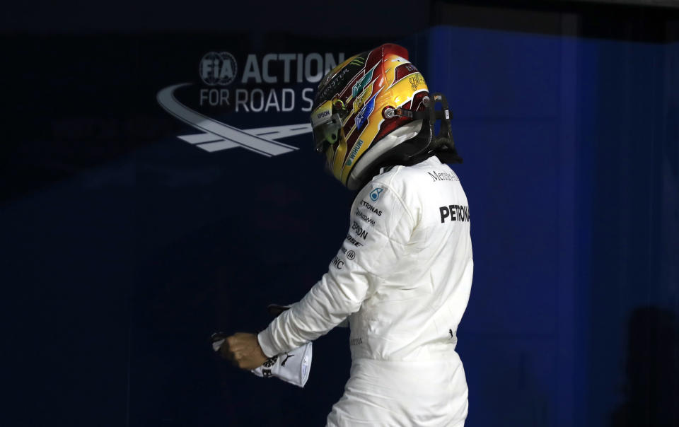 Mercedes driver Lewis Hamilton of Britain takes his gloves off after he clocked the second fastest time during the qualifying session for the Bahrain Formula One Grand Prix, at the Formula One Bahrain International Circuit in Sakhir, Bahrain, Saturday, April 15, 2017. The Bahrain Formula One Grand Prix will take place on Sunday. (AP Photo/Hassan Ammar)