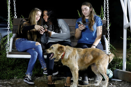 Israeli teens, Meshy Elmkies (R), 16, Liam Yefet (C), 16 and Lee Cohen, 17, co-managers of Instagram account, Otef.Gaza, look at their mobile phones as they sit on a swing at Kibbutz Kerem Shalom which borders the Gaza Strip, in southern Israel November 11, 2018. Picture taken November 11, 2018. REUTERS/Amir Cohen