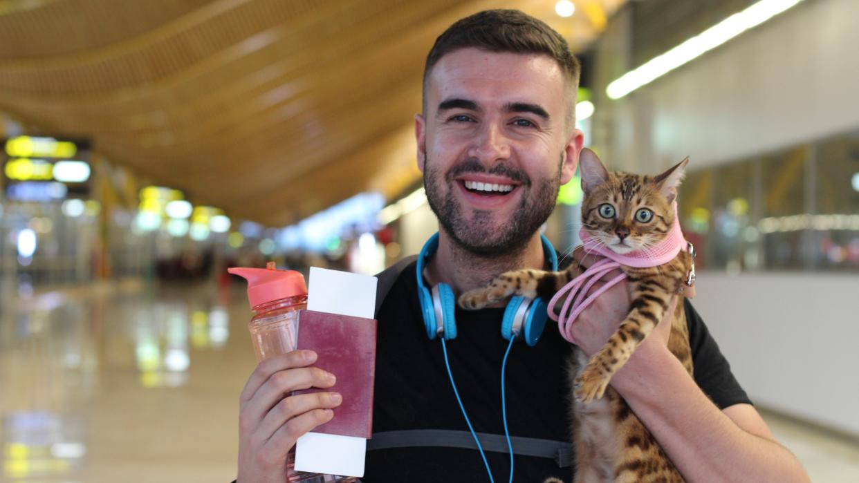  Happy man holding his cat at the airport. 