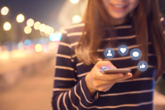 A woman checks social media messages on her phone.