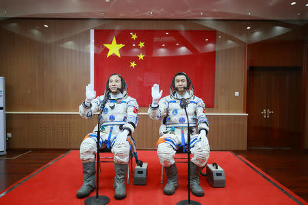 Chinese astronauts Jing Haipeng (L) and Chen Dong wave in front of a Chinese national flag before the launch of Shenzhou-11 manned spacecraft, in Jiuquan, China, October 17, 2016. REUTERS/Stringer