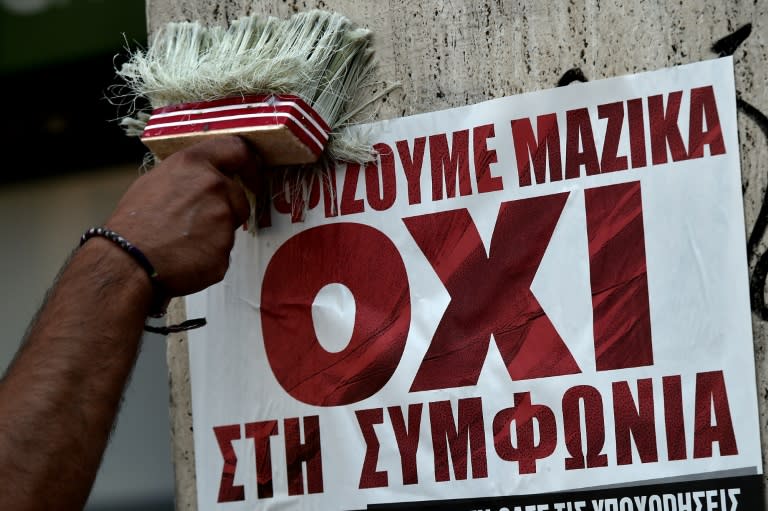 A man plasters a poster that reads, "We vote NO to the agreement", in Athens