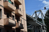 Buildings stand next to the partially collapsed Morandi highway bridge in Genoa, Italy, Thursday, Aug. 16, 2018. The death toll from the collapse of a highway bridge in the Italian city of Genoa that is already confirmed to have claimed 39 lives will certainly rise, a senior official said. Interior Minister Matteo Salvini told reporters: "Unfortunately, the toll will increase, that's inevitable." Searchers continued to comb through tons of jagged steel, concrete and dozens of vehicles that plunged as much as 45 meters (150 feet) into a dry river bed on Tuesday. (Luca Zennaro/ANSA via AP)