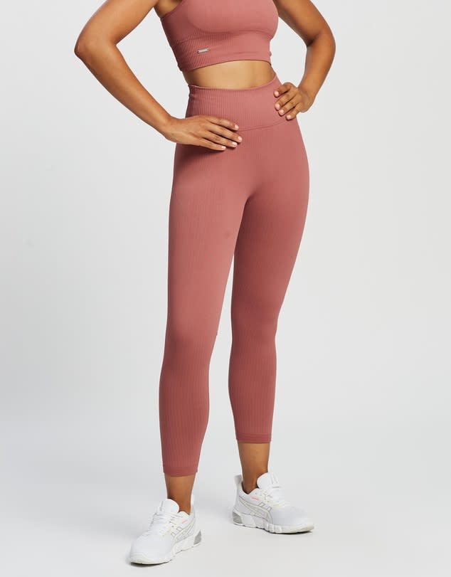 Woman from waist down wearing ochre crop top and Aim'n Ribbed Seamless 7/8 Tights and runners.