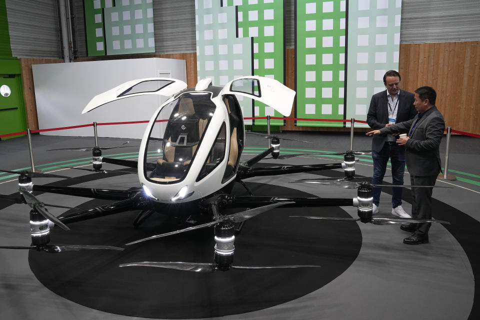 People talk by the eHang autonomous aerial vehicle at the Paris Air Show, Wednesday, June 21, 2023 in Le Bourget, north of Paris. Aviation industry CEOs and top government officials from around the world descended on the Paris Air Show for a week of deal-making and demonstrations of the world's latest air and space technology. (AP Photo/Michel Euler)