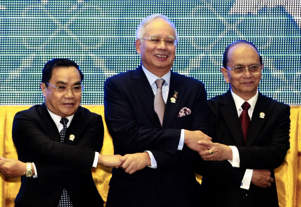 Leaders from the Association of Southeast Asian Nations (ASEAN) from left, Laos' Prime Minister Thongsing Thammavong, Malaysia's Prime Minister Najib Razak and Myanmar's President Thein Sein join hands during a group photo at the opening ceremony of the 20th ASEAN Summit in Phnom Penh, Cambodia Tuesday, April 3, 2012. (AP Photo/Apichart Weerawong)