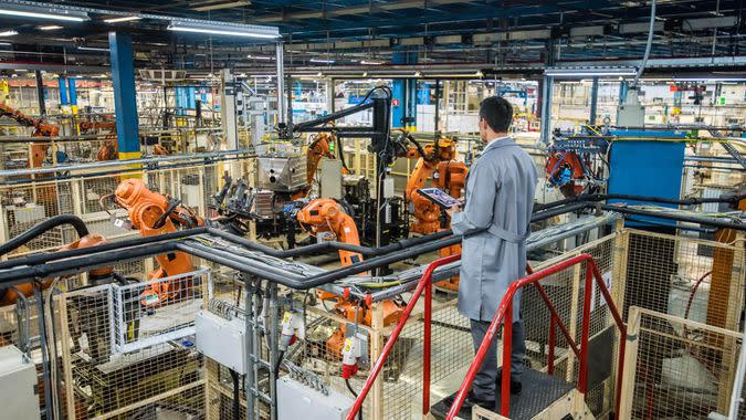 Male factory engineer inspecting the work process of the robots performing their operations in appliance manufacturing factory.