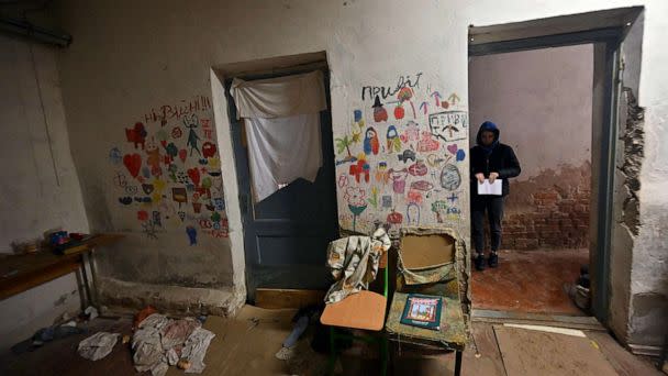 PHOTO: A visitor stands next to children drawings in the basement of a school where villagers were kept for almost a month by Russian troops in the village of Yahidne, north of Kyiv, a year after the liberation of the settlement, April 3, 2023. (Sergei Supinsky/AFP via Getty Images)