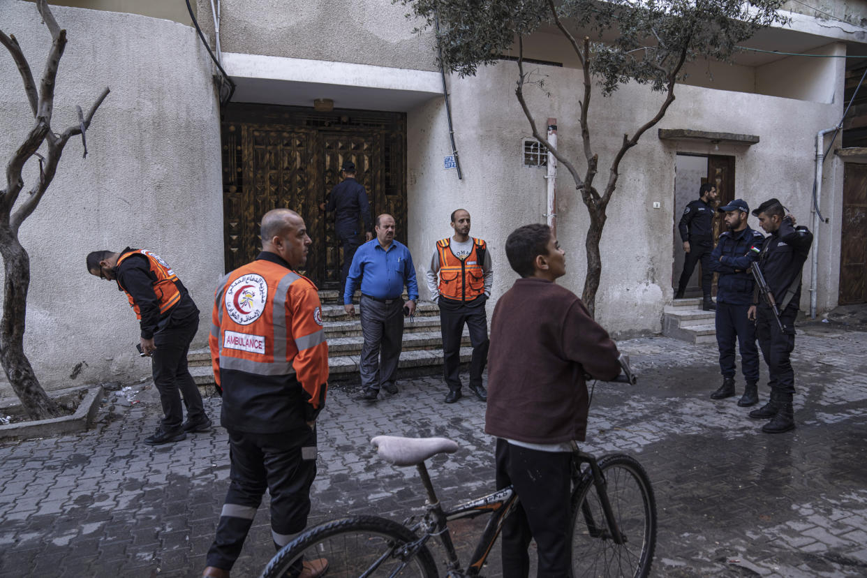 Members of the police and civil defense stand in front of a three story building where a deadly fire broke out in the Jebaliya refugee camp, northern Gaza Strip, Friday, Nov. 18, 2022. A fire set off by stored gasoline in a residential building killed 21 people Thursday evening in a refugee camp in the northern Gaza Strip, the territory's Hamas rulers said, in one of the deadliest incidents in recent years outside the violence stemming from the Israeli-Palestinian conflict. (AP Photo/Fatima Shbair)