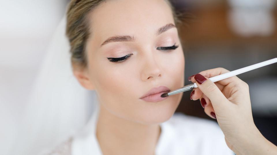 bride looks down while make up artist puts the lipstick on her 