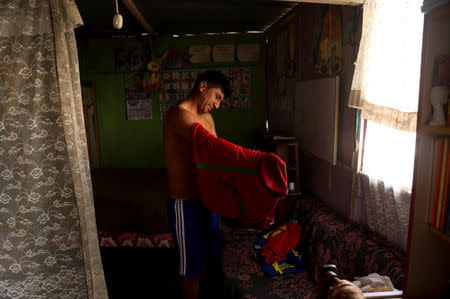 Saul Acevedo, a resident of Nueva Union shantytown who plays soccer at a makeshift soccer field, dresses at his home before a soccer match in Villa Maria del Triunfo district of Lima, Peru, May 27, 2018. REUTERS/Mariana Bazo