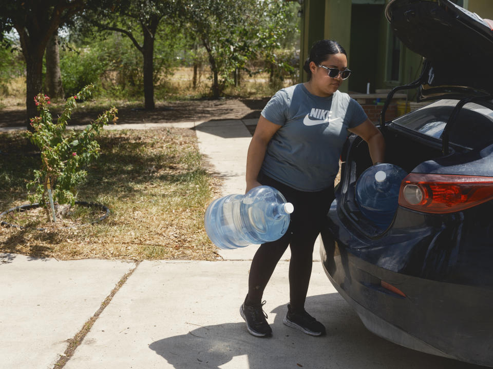 Kathy Quilatan descarga tinajas de agua en su casa en la colonia Pueblo de Palmas, donde su familia se ha quedado sin agua durante semanas este verano, en Peñitas, Texas, el 24 de julio de 2023. (Jordan Vonderhaar/The New York Times)